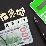 calculators, banknotes and house shapes with the word REIT or real estate investment trust