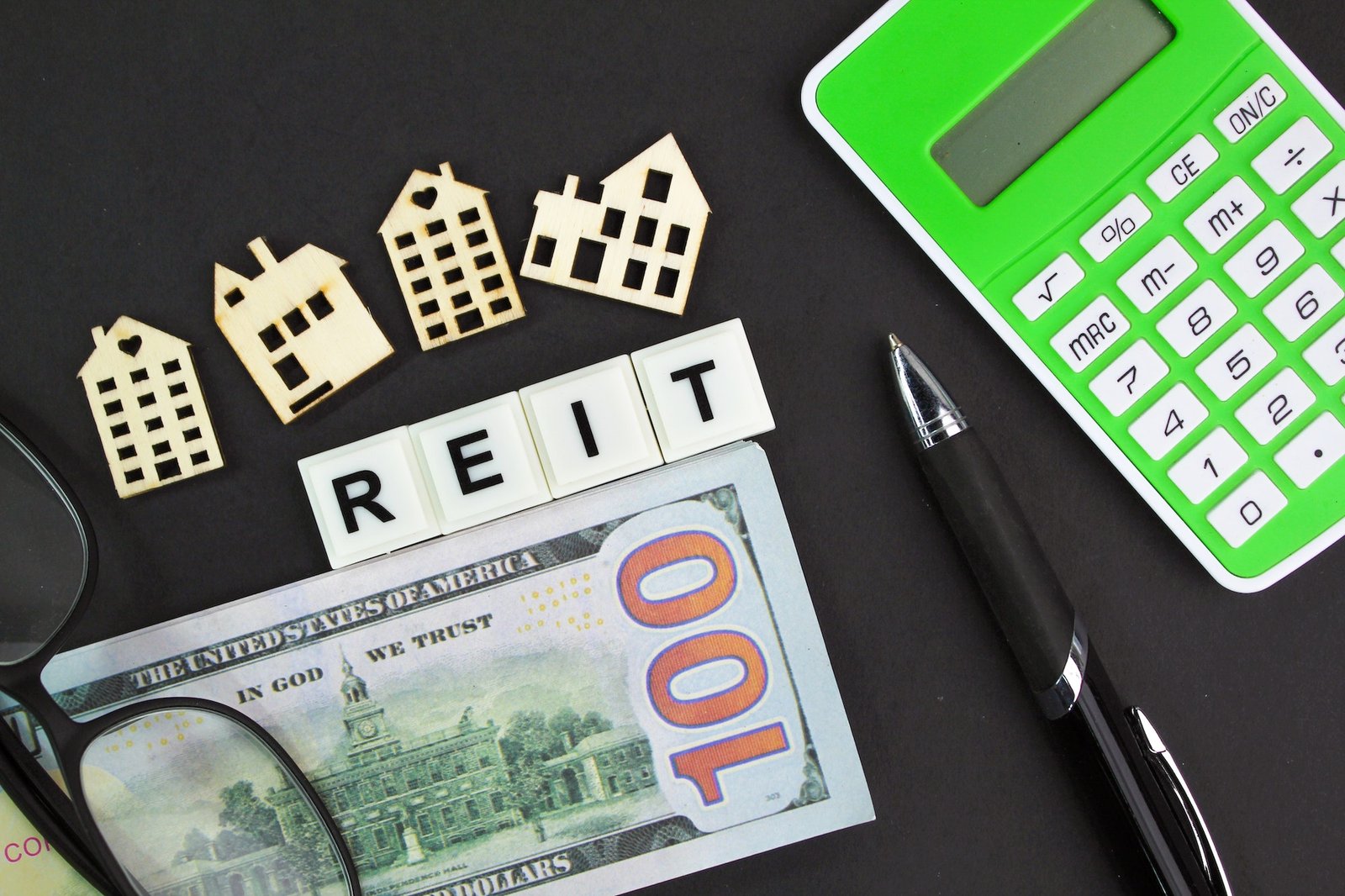 calculators, banknotes and house shapes with the word REIT or real estate investment trust